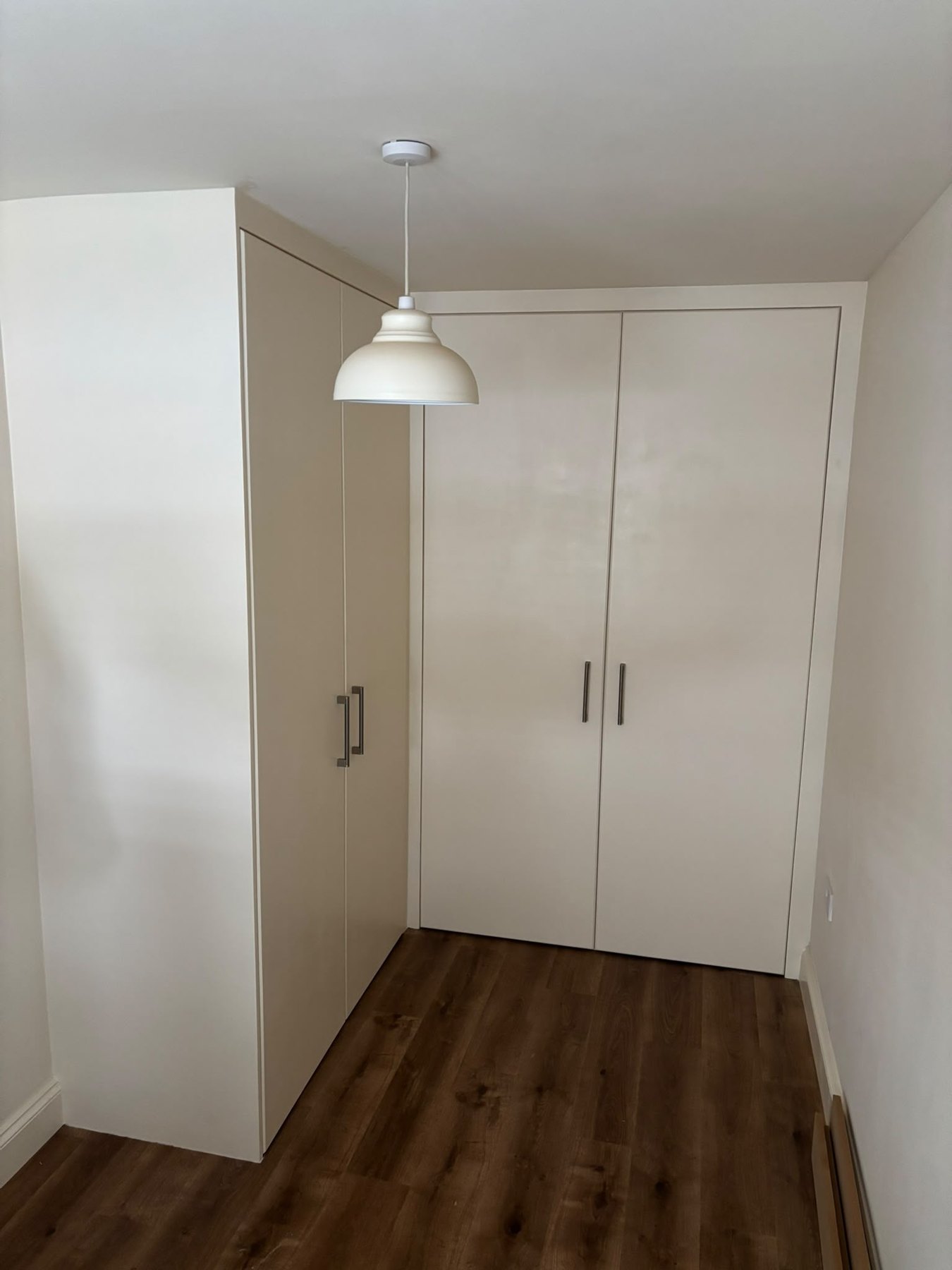 Tall painted fitted cupboards built into a corner, floor to ceiling