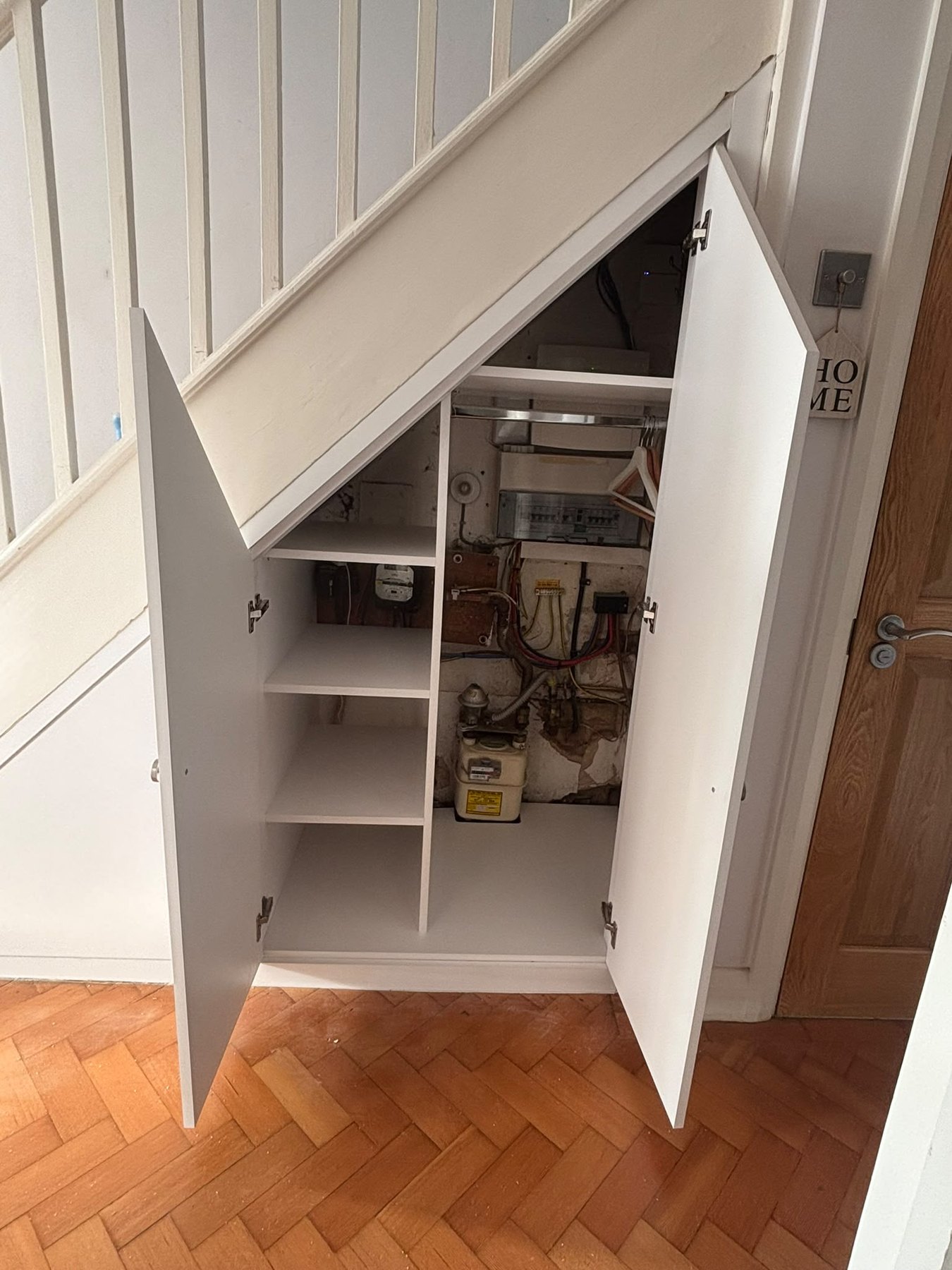 Understairs cupboard opened to show the boiler and pipework boxed in behind doors, with full access kept for servicing
