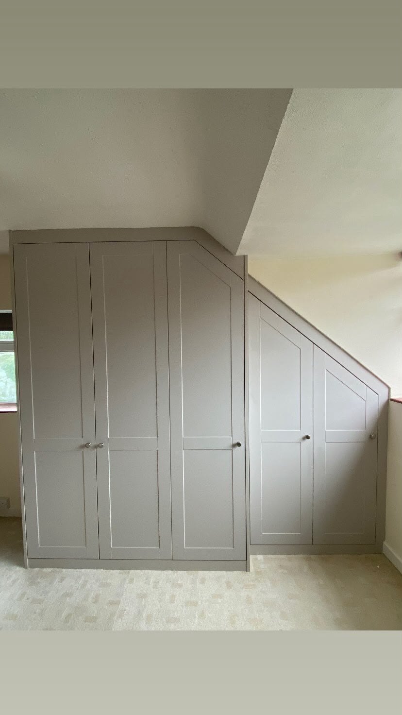 Painted storage cupboard built into the angled space beneath a staircase