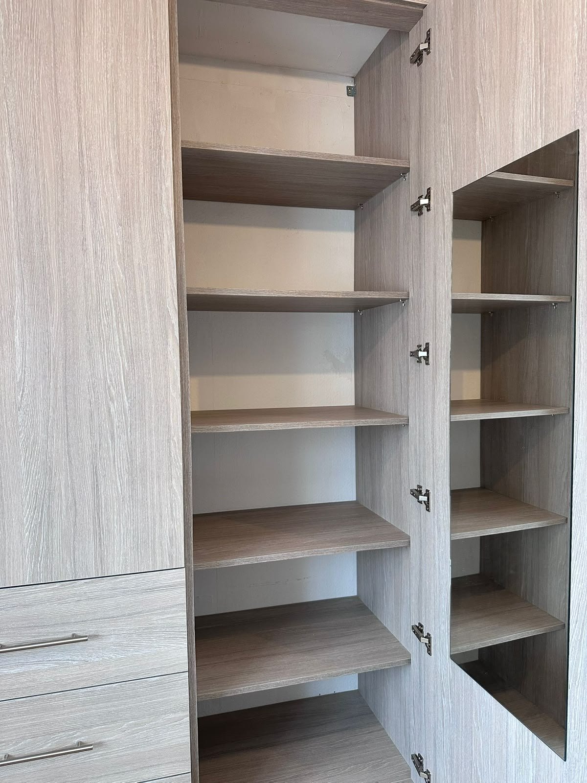 Adjustable shelving column in the Feltham wardrobe with a full-length mirror fitted to the inside of the door