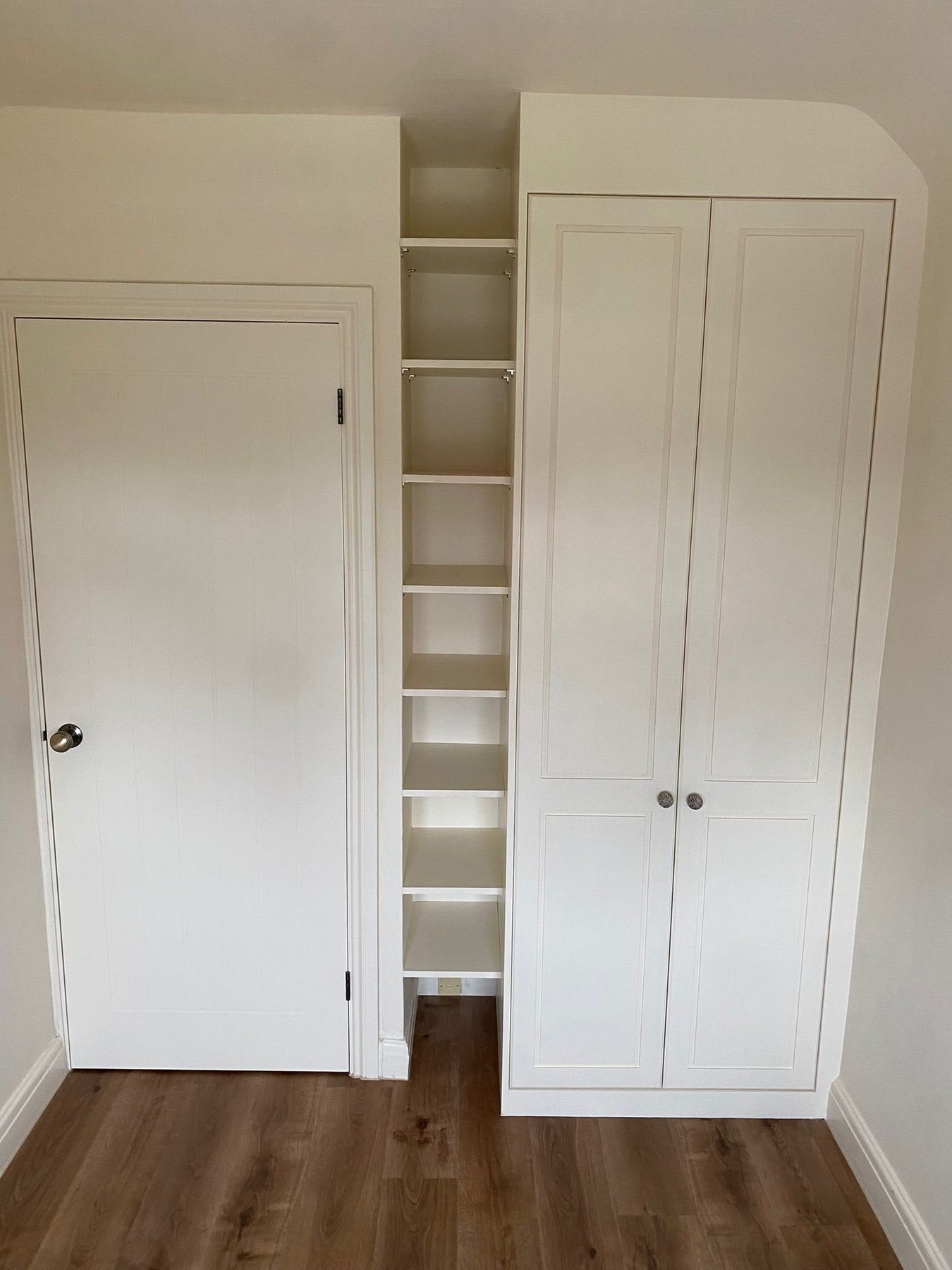 Painted fitted wardrobe alongside a full-height open shelving column